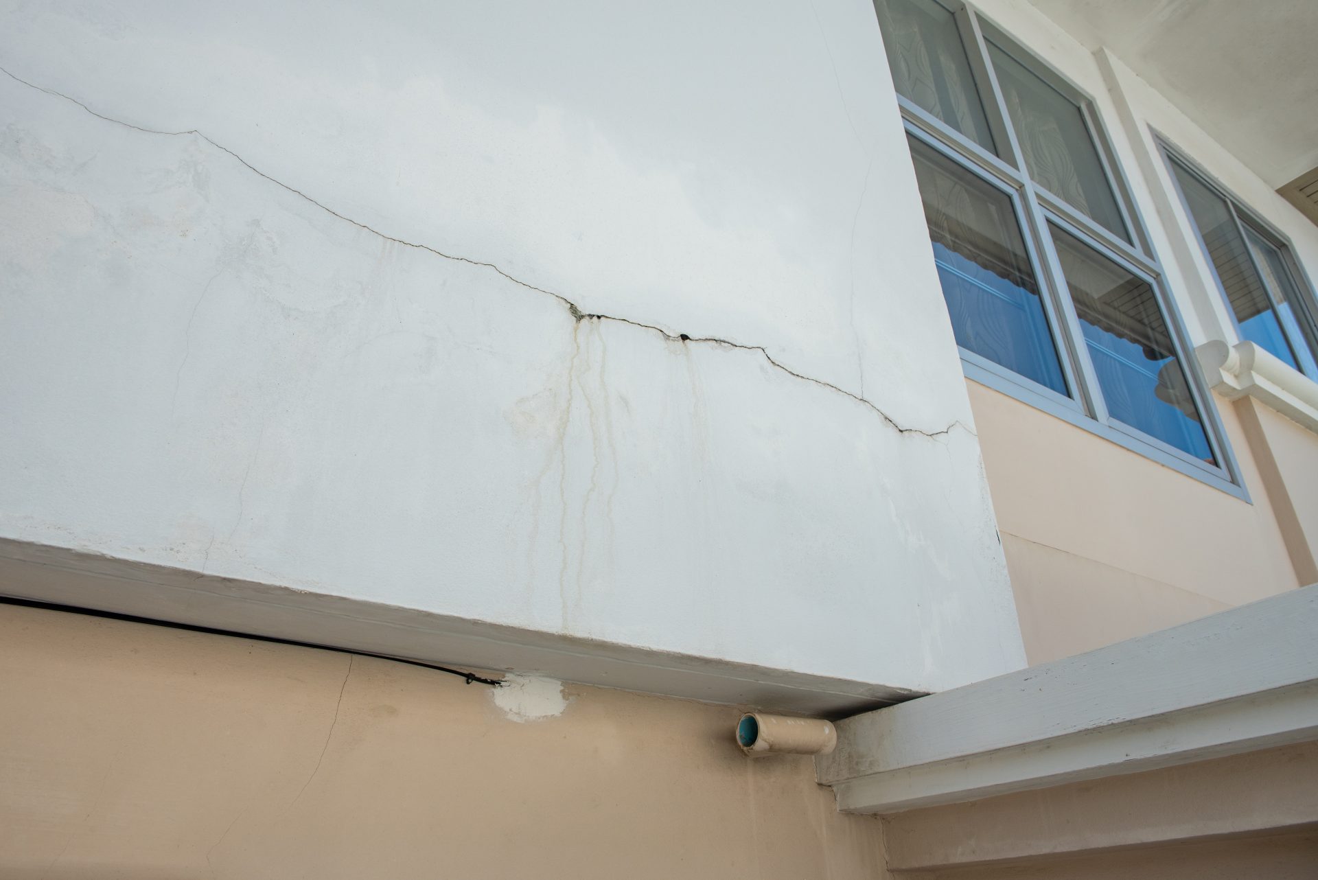 Fasada hiše, prekrita z zelenimi algami, ki kaže potrebo po čiščenju.